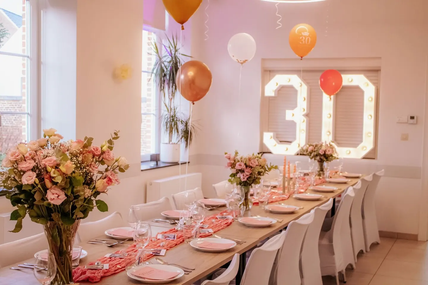Lichtcijfers 30 boven een gedekte feesttafel met ballonnen