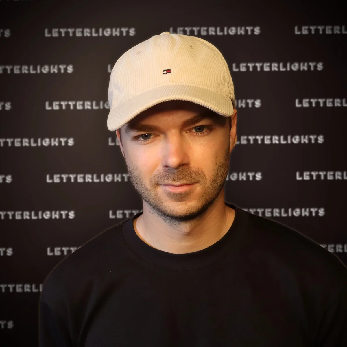 Mathys, met beige pet en zwarte trui, voor de LetterLights-backdrop